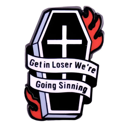A black coffin with a white cross, wrapped in a Get in loser were going sinning ribbon, features red flames on the top right and bottom left, plus a Gothic spider pin for extra dark flair.