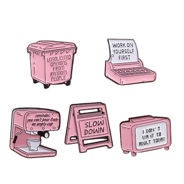 Five pink enamel pins are displayed on a beige surface, each featuring a motivational or funny message with unique designs: trash bin, laptop, espresso machine, caution sign, and retro TV.