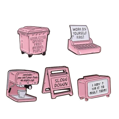 Five pink enamel pins are displayed on a beige surface, each featuring a motivational or funny message with unique designs: trash bin, laptop, espresso machine, caution sign, and retro TV.