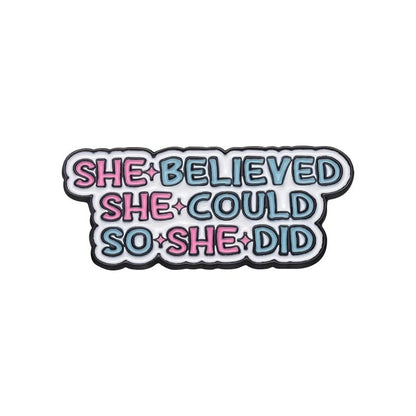 Enamel pin features “She believed she could so she did” in bold pink and blue—an empowering, stylish feminist accessory that makes a statement.