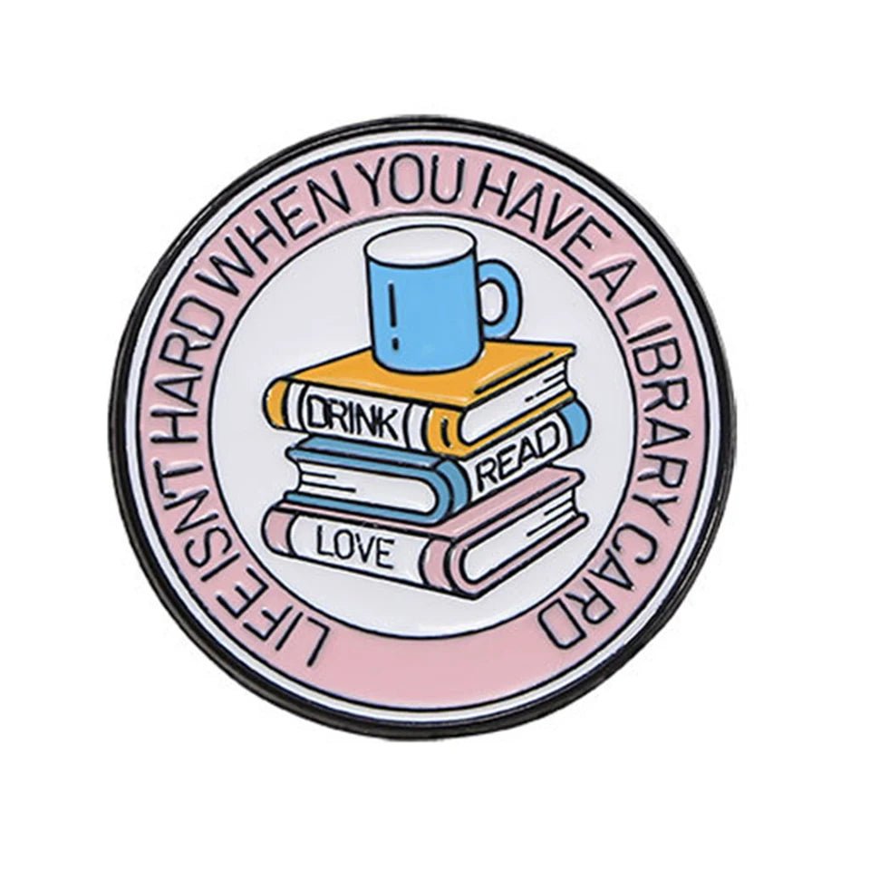 Round enamel pin features a blue mug atop three stacked books labeled DRINK, READ, and LOVE. The rim says LIFE ISNT HARD WHEN YOU HAVE A LIBRARY CARD—a perfect gift for book or romance lovers.