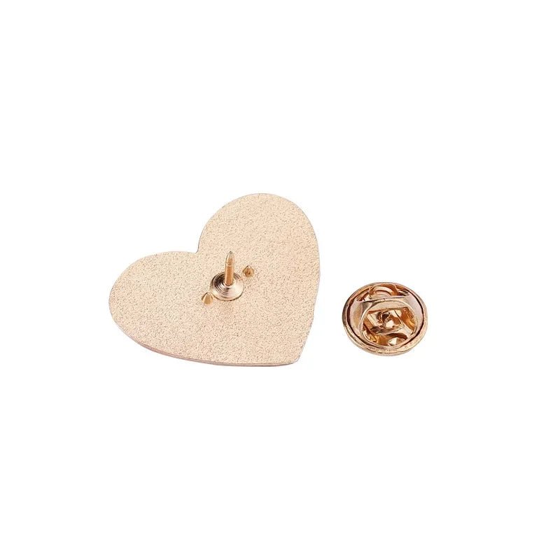 A gold-tone heart-shaped enamel pin  featuring a textured surface and matching round backing, rests on a white background—a charming accessory for any Cute But Psycho collection.