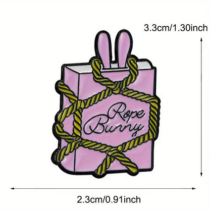 A pink box with bunny ears, “Rope Bunny” text, and yellow rope. This enamel pin is 3.3 cm tall by 2.3 cm wide