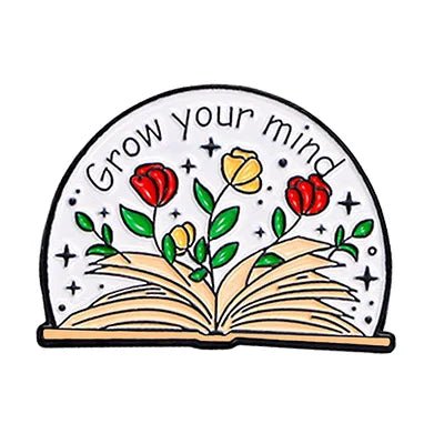 An open book with vibrant flowers and green leaves sprouts from its pages. Grow your mind floats above. Perfect for Romance Readers or enamel pin collectors, this badge features scattered stars in the background.