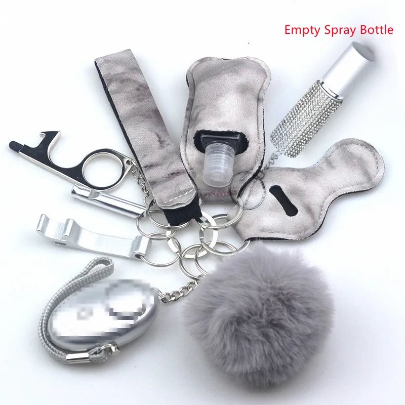 The Kiss Me Later keychain set includes a grey pom-pom, metallic bottle opener, silver clip, empty spray bottle in a holder (labeled in red), decorative bottle, and fuzzy case—ideal for outdoor activities and personal safety.