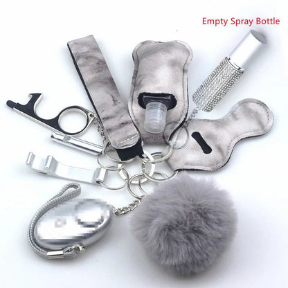 The Kiss Me Later keychain set includes a grey pom-pom, metallic bottle opener, silver clip, empty spray bottle in a holder (labeled in red), decorative bottle, and fuzzy case—ideal for outdoor activities and personal safety.