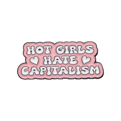 Enamel pin features a pink and white bubble design that reads “HOT GIRLS HATE CAPITALISM” with two heart accents—a bold feminist accessory.