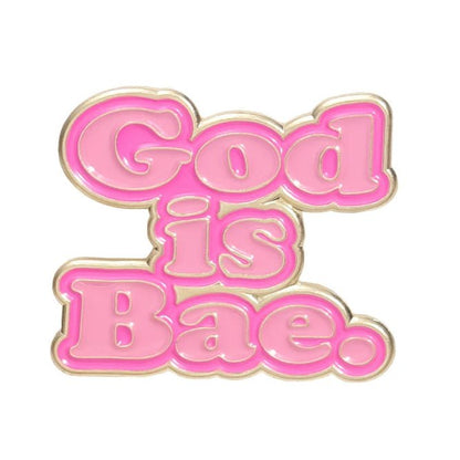 My Cutesy Era’s pink enamel pin features bold, bubble letters spelling God is Bae in gold on a white background.