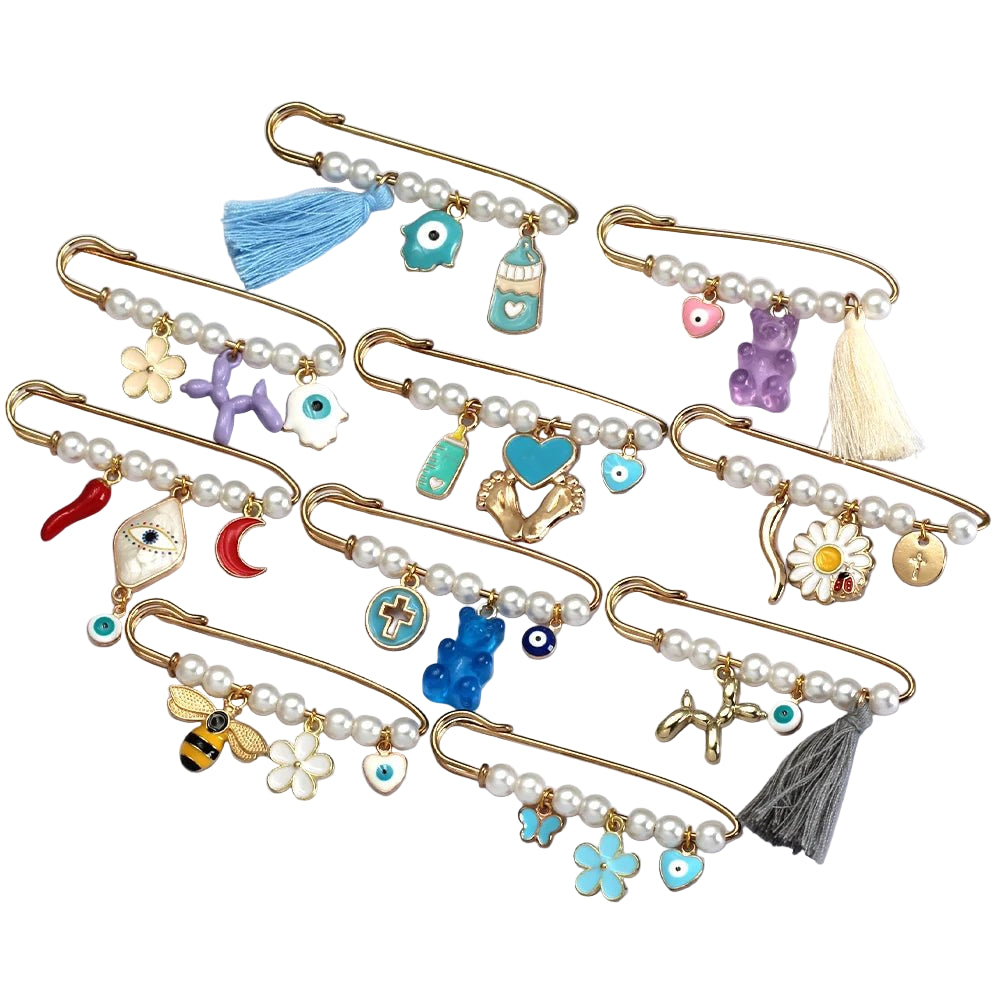 A set of Kiss Me Later decorative gold baby safety pins, each featuring pearls and colorful beads, with brooch designs like flowers, hearts, animals, evil eye motifs, and tassels—arranged neatly on a white surface.