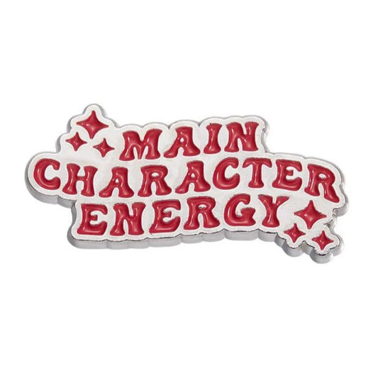 Add a spark to your day with My Cutesy Era’s motivational enamel pin: bold red “MAIN CHARACTER ENERGY” letters outlined in white and surrounded by small stars—a positive affirmation for daily inspiration.