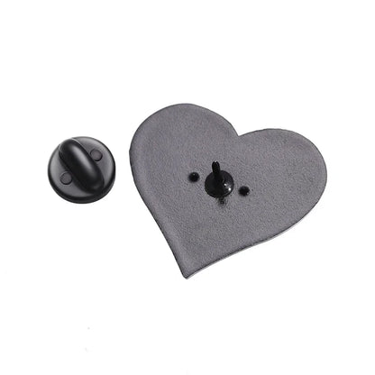 Gothic black metal heart-shaped pin badge with a sharp center post, displayed beside its round black clutch backing on a white background.