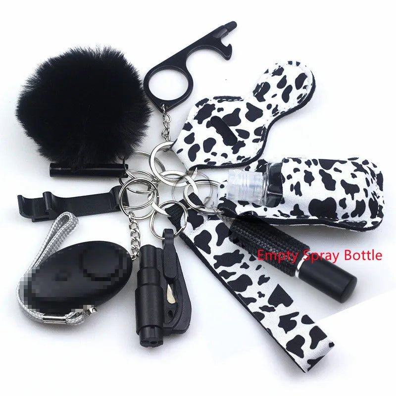 The Kiss Me Later keychain set includes a black pom-pom, cow-print case, empty spray bottle, touch tool, and whistle on sturdy metal rings—perfect personal safety accessories for outdoor adventures in stylish matching black and cow-print designs.