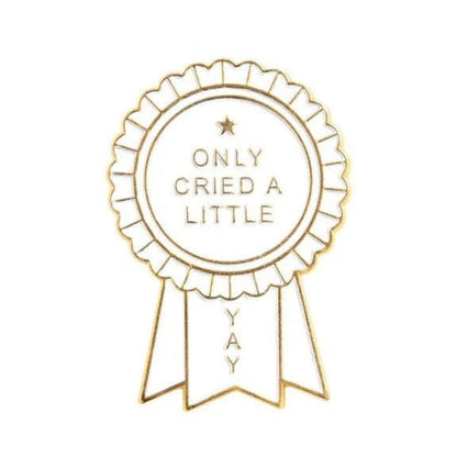 A gold and white enamel pin award ribbon by My Cutesy Era, featuring ONLY CRIED A LITTLE in the center and YAY on a ribbon tail.