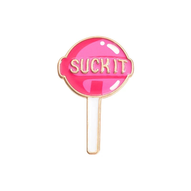 The Suck It pin is a playful pink lollipop enamel pin with SUCK IT in gold across the candy and a white stick—add a sweet touch to any outfit with this fun accessory.
