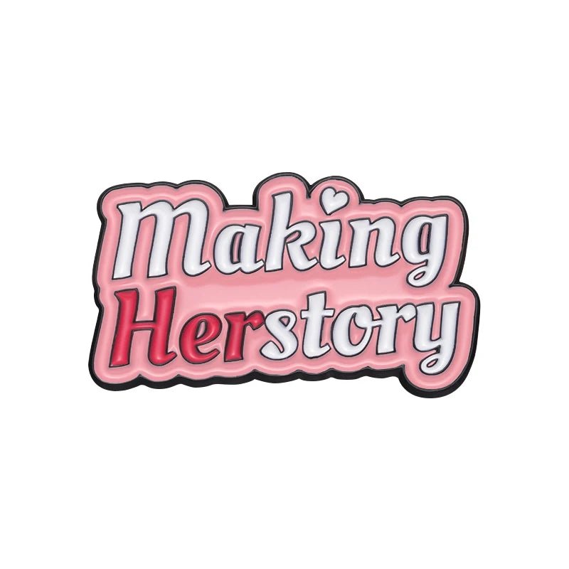 Feminist Pin features Making Herstory in white and red cursive on pink, with a heart above the i—perfect for your enamel pin collection.