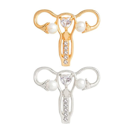 Uterus ovary pins in gold and silver, featuring heart-shaped gems, pearls on the sides, and round gems on the stem—an elegant feminist gift honoring strength and beauty.
