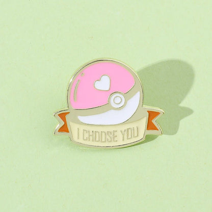 enamel pin shaped like a pink Poké Ball with a heart and I CHOOSE YOU on a ribbon, set on light green. Perfect for any Pokémon fan!.