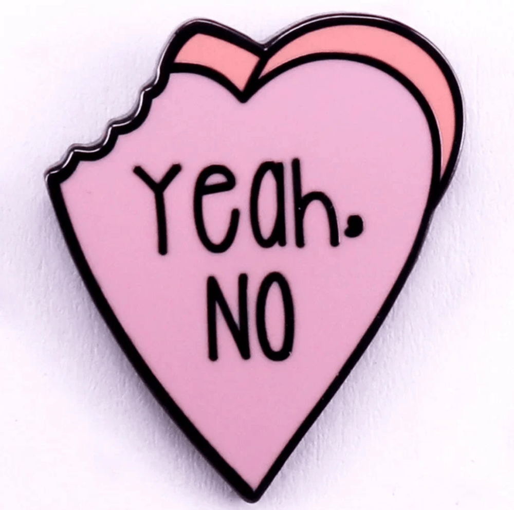 PINK Red enamel pin is shaped like a bitten pink heart with bold black Yeah. NO. text. Both the outline and lettering are strikingly bold and black, giving this playful accessory eye-catching appeal.
