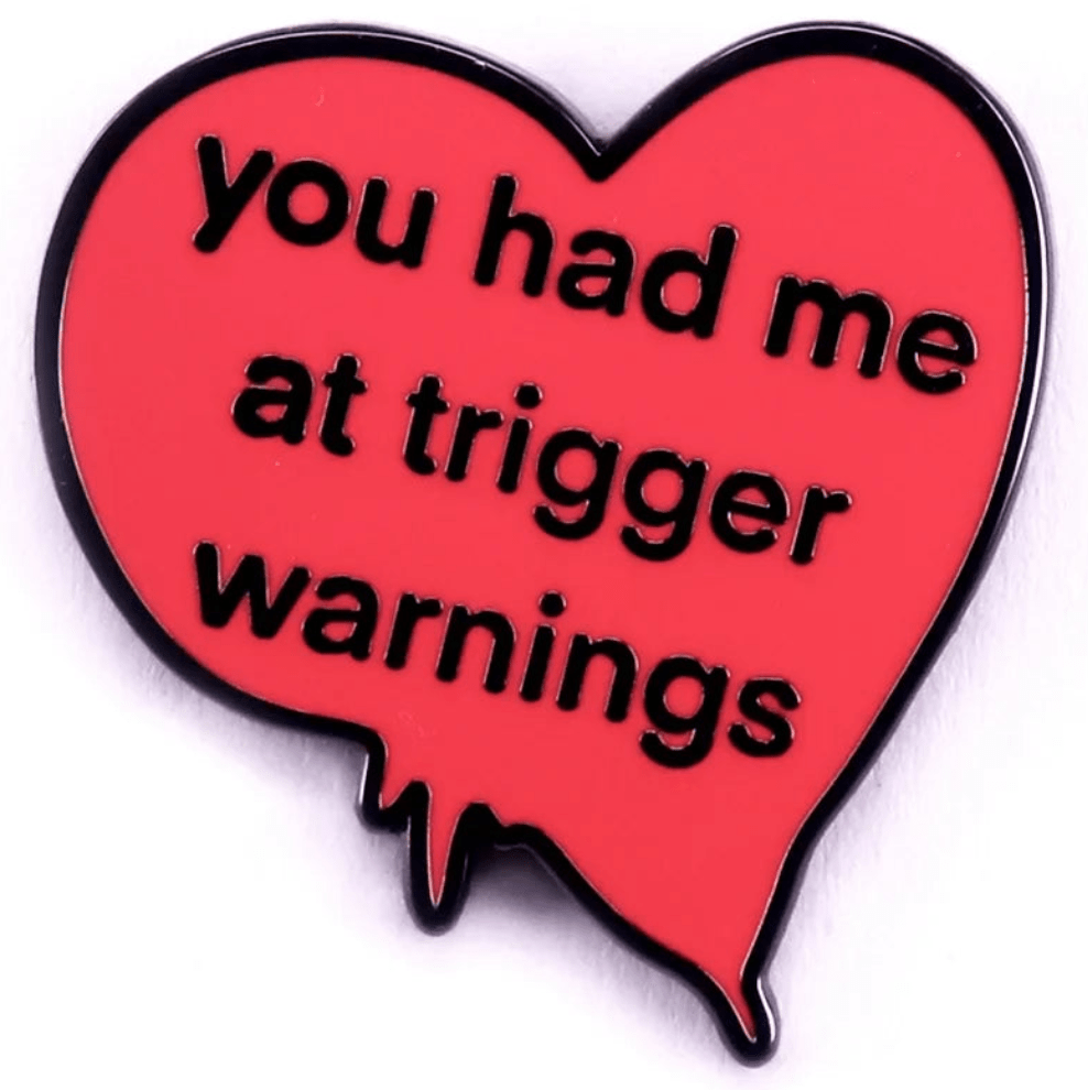 Red, irregular heart pin with black edging features you had me at trigger warnings in bold black letters—perfect for fans of quirky accessories and pink love heart enamel pins.