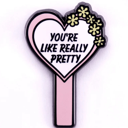 Show your Rainbow Pride with this  pink heart-shaped enamel pin, featuring yellow flowers, bold black “YOURE LIKE REALLY PRETTY” text, and a charming design—perfect for accessorizing any look.