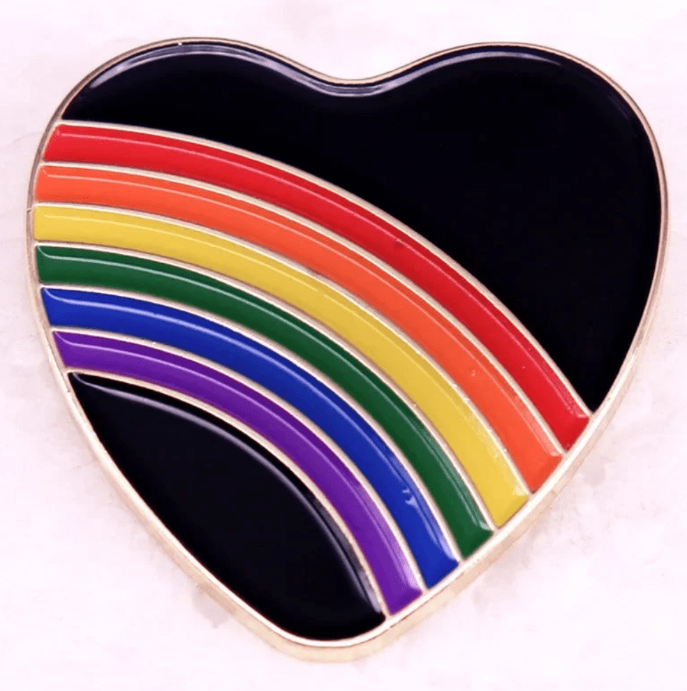 Pride love heart enamel pin with a black background features a rainbow with red, orange, yellow, green, and purple stripes arcing across it.