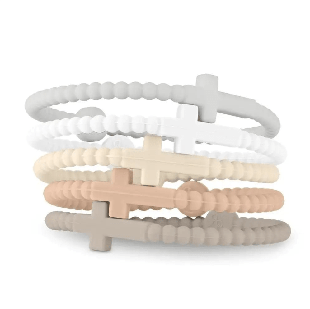 Five Kiss Me Later Jesus Bracelets, crafted from non-toxic silicone, are stacked on a white background. Each Cutie Bracelet features a cross design and comes in neutral shades: grey, white, beige, tan, and taupe.