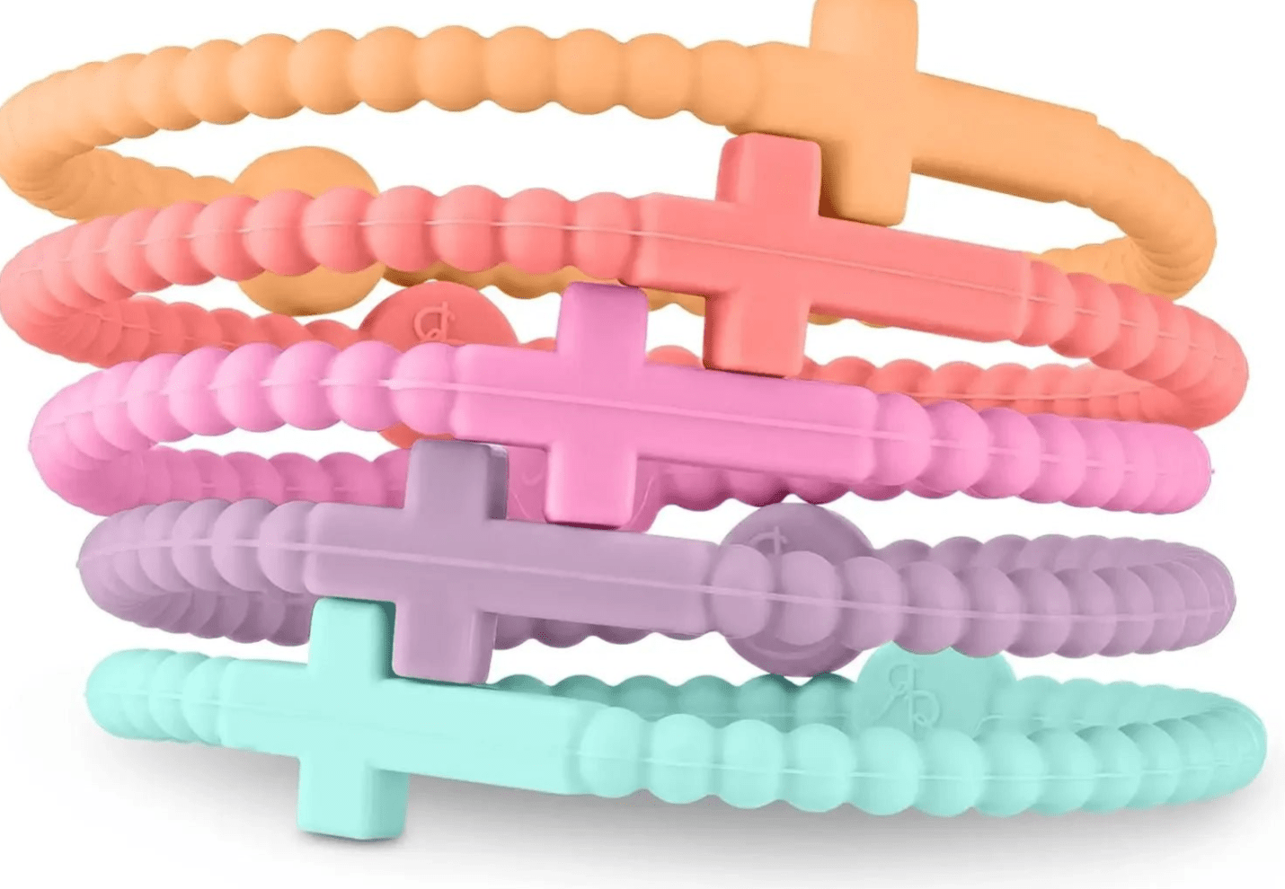Five textured, non-toxic silicone Cutie Bracelets by Kiss Me Later in pastel orange, coral, pink, purple, and mint are stacked together. Each features a raised cross detail and a small round accent.