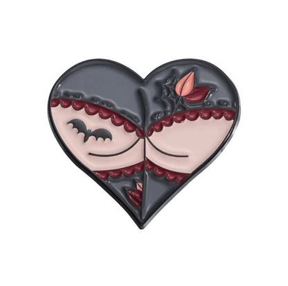 Heart-shaped pin with a gothic design: two closed eyes, black bat, spiderweb, skeleton hands, and red leaf on a gray and pale background with scalloped maroon edges.