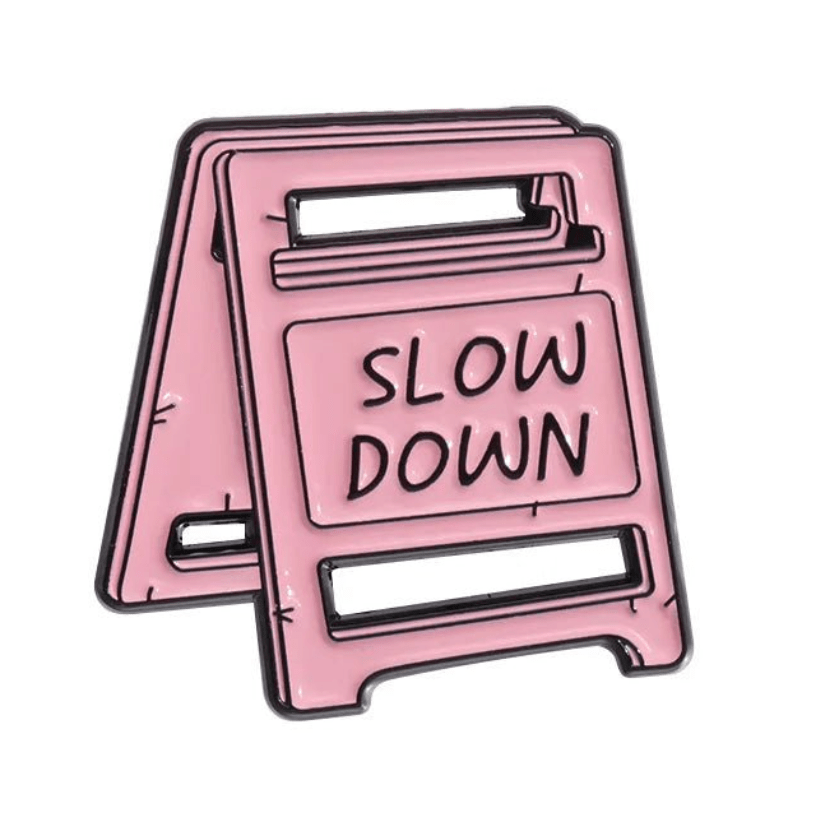 An illustration of a pink A-frame caution sign featuring the words SLOW DOWN in large capital letters on the front.