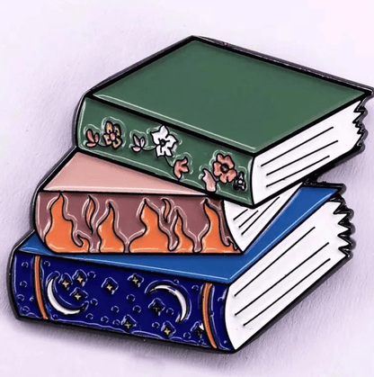 Three illustrated books are stacked: on top, a green floral book for Romance Readers sits above a pink one with flames and a blue one adorned with moons and stars against a light background.