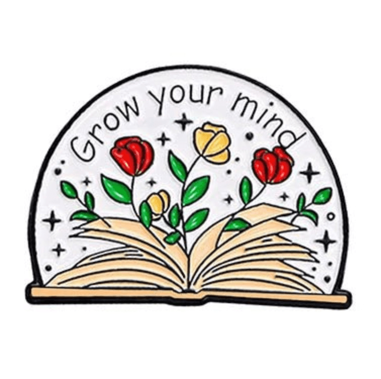 An open book with colorful flowers and green leaves grows from its pages, surrounded by sparkles. Grow your mind curves above—a perfect enamel pin for romance readers or book lovers 