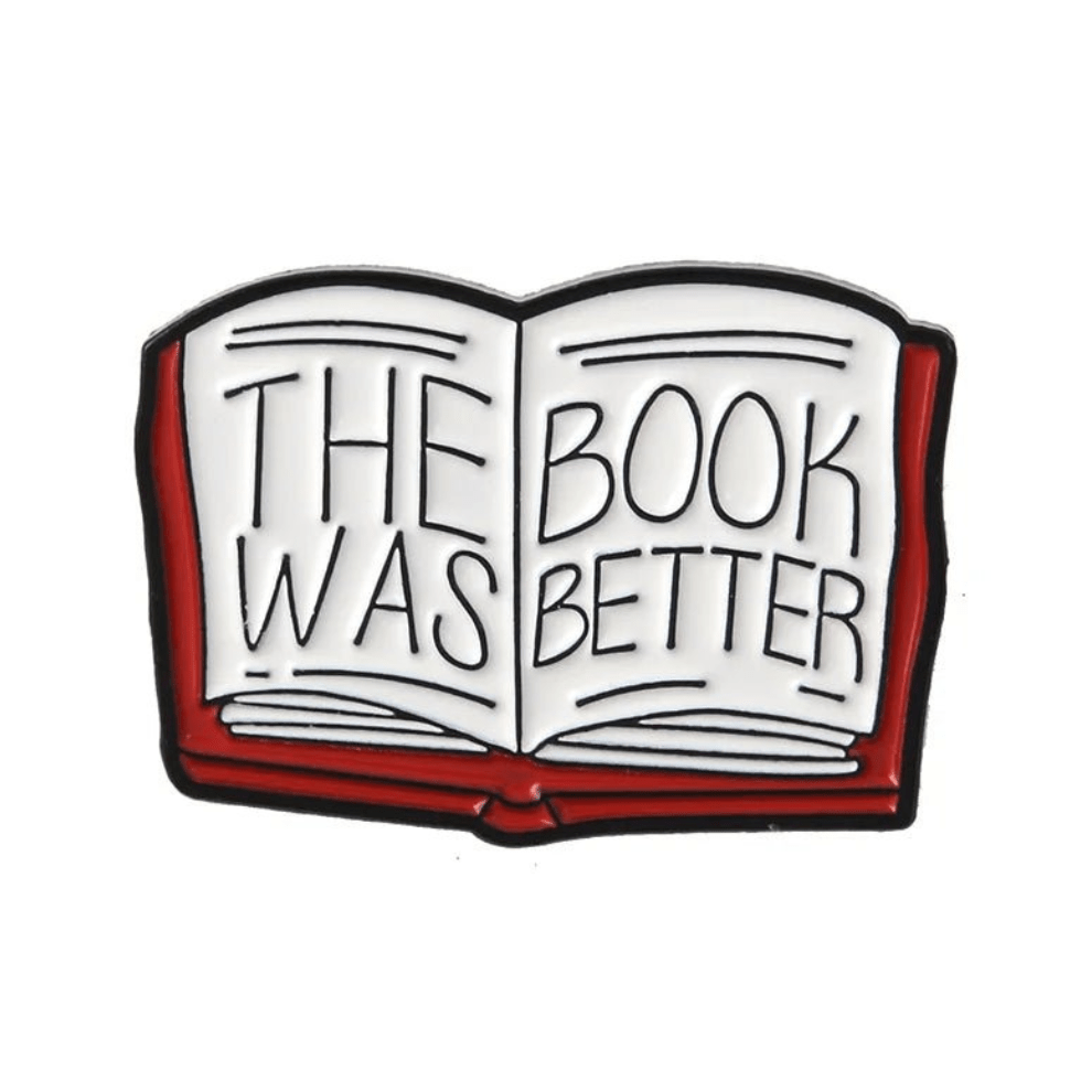 An enamel pin shaped like an open book with THE BOOK WAS BETTER in bold letters on its pages, featuring a red cover and black outlines—ideal for book lovers or romance readers.