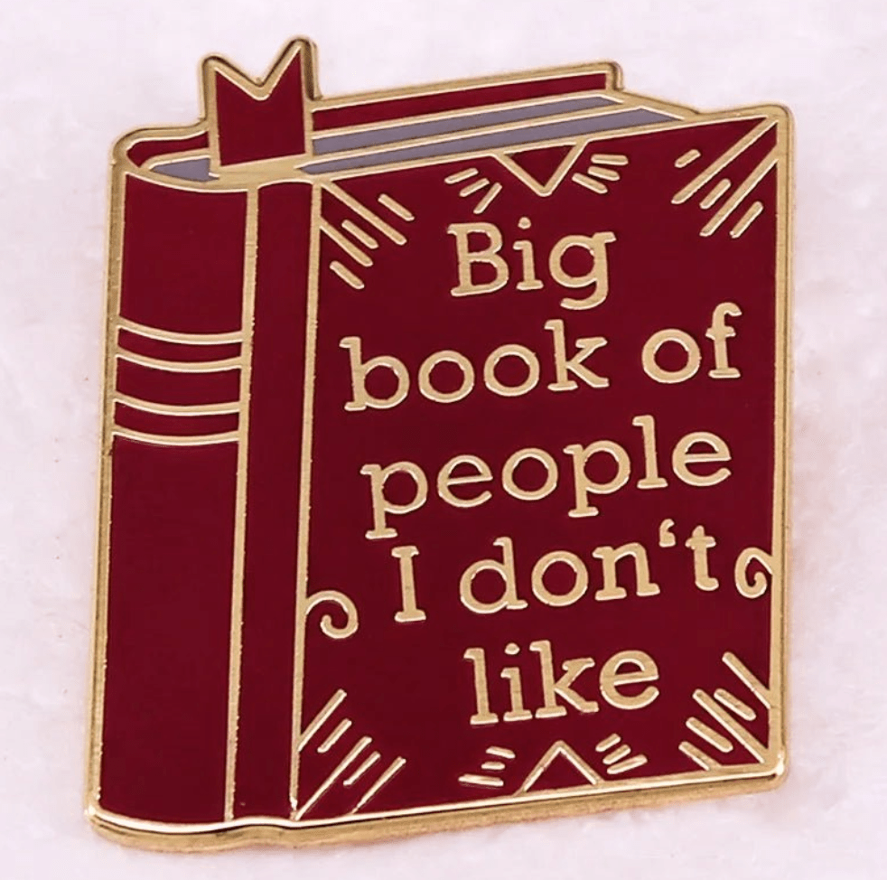 Kiss Me Later’s red enamel pin, shaped like a book with gold trim and accents, features “Big book of people I don’t like”—a witty choice for enamel pin collectors and book lovers alike.