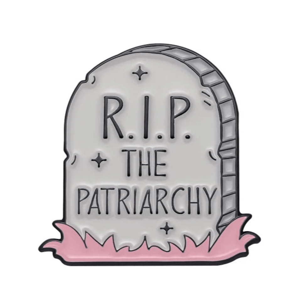 Enamel pin featuring a cartoon tombstone with R.I.P. THE PATRIARCHY, pink grass, and star details—perfect for feminist pin fans.