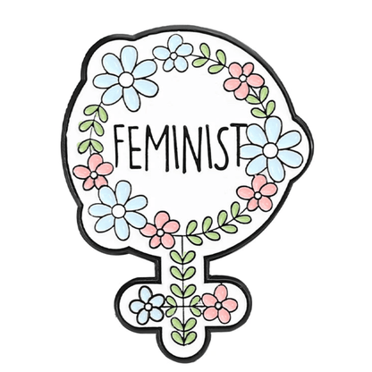 A feminine symbol outlined in black with blue and pink flowers plus green leaves forms a striking enamel pin, featuring the word FEMINIST in bold black letters at its center.