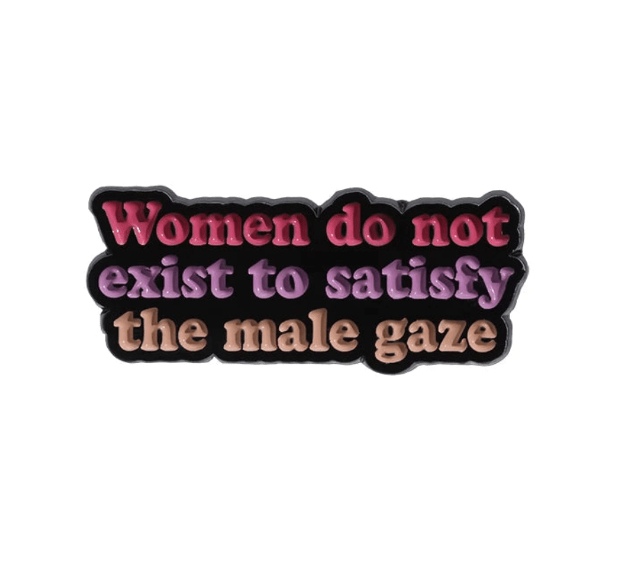 Text badge features “Women do not exist to satisfy the male gaze” in pink, purple, and tan on black—styled like a Patriarchy Tombstone. Perfect for fans of empowering feminist pins!.
