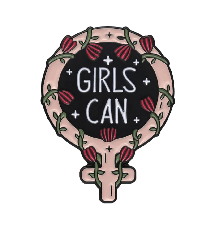 Enamel pin features a pink-outlined feminine symbol with red flowers and green vines around a black center bearing “GIRLS CAN” in white—an empowering accessory for any feminist pin collection.