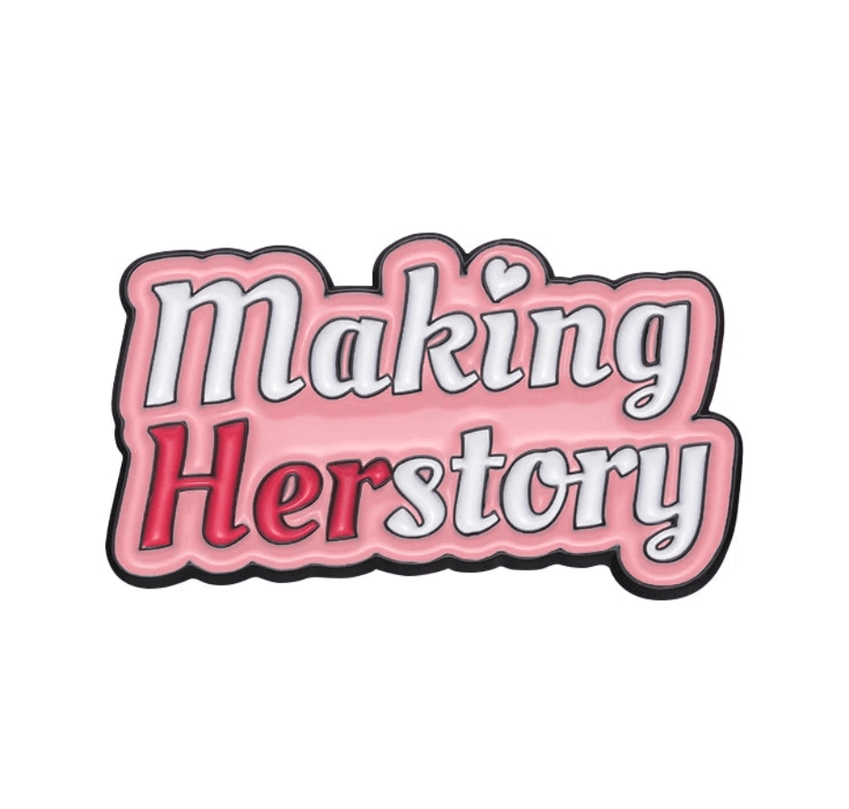 Pink enamel pin says “Making Herstory” in a bold, playful font, with “Her” in red and a heart over the “i”—a standout piece among feminist pins.