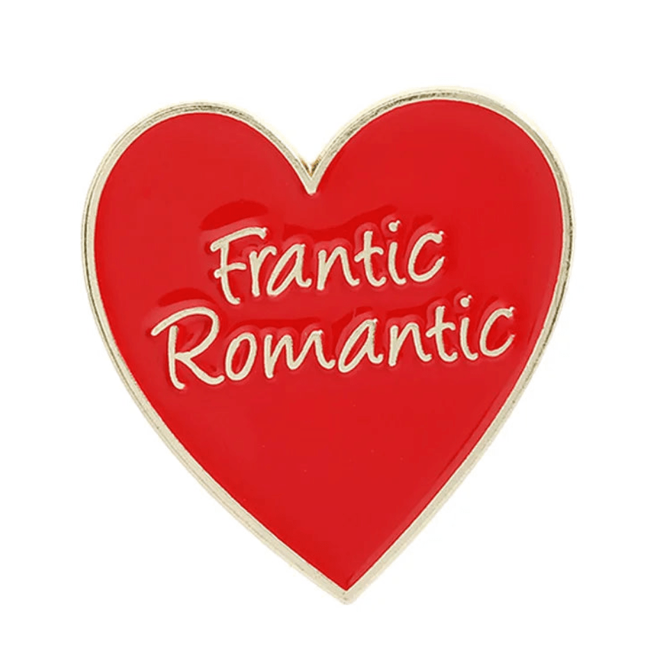 A heart-shaped red and gold enamel pin features gold edges and “Frantic Romantic” in white script across the center.