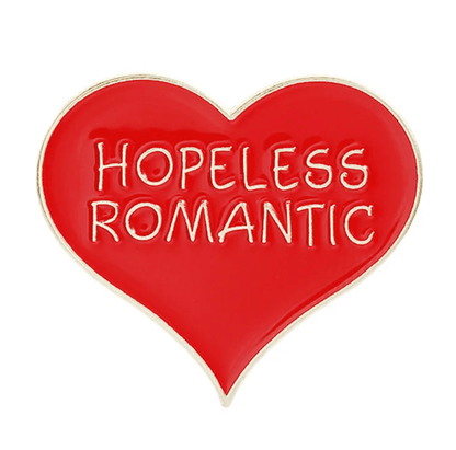 A red and gold heart-shaped enamel pin featuring the words HOPELESS ROMANTIC in bold white letters at the center.