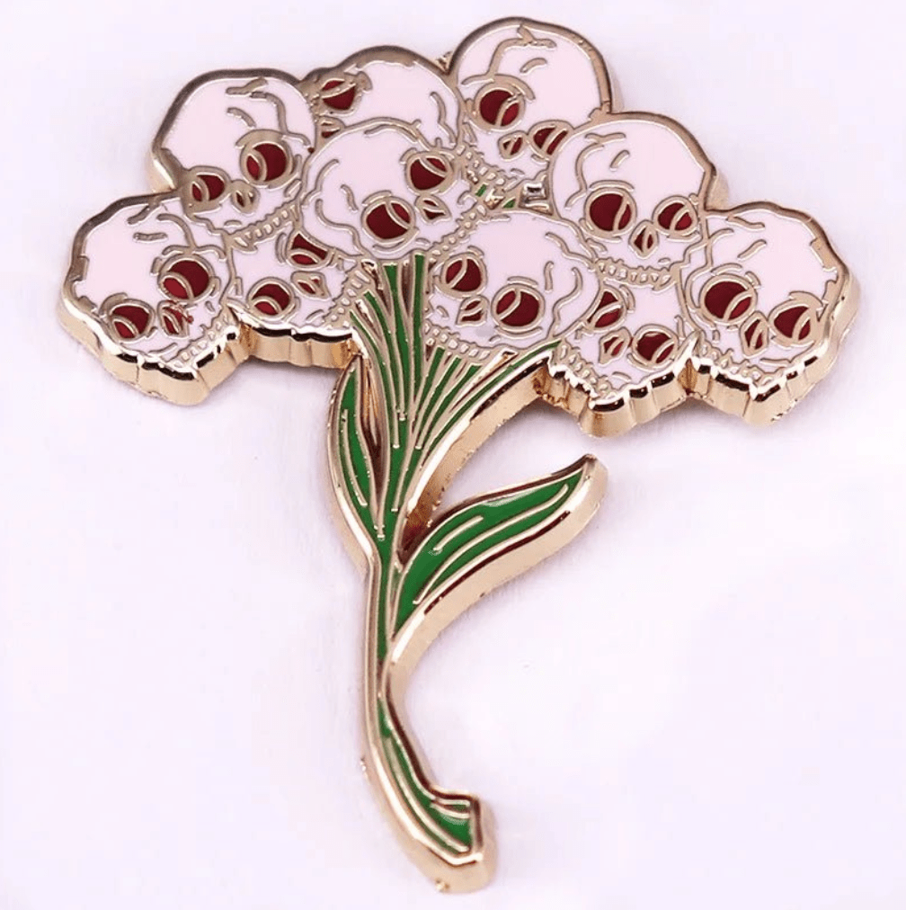 pin features a flower bouquet design with skulls as blossoms and green stems and leaves, creating a bold skull flower arrangement on a white background.