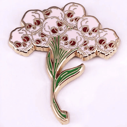 pin features a flower bouquet design with skulls as blossoms and green stems and leaves, creating a bold skull flower arrangement on a white background.
