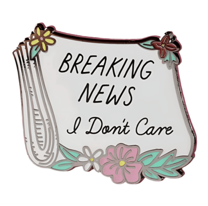 My Cutesy Era enamel pin shaped like a newspaper with flowers, featuring “BREAKING NEWS I Don’t Care” in bold black letters.