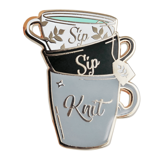 Three stacked mugs with Sip, Sip, and Knit in silver outline adorn this My Cutesy Era enamel pin. Perfect for Black Sheep Club, it features leaves, a tea tag, and a star on each mug.