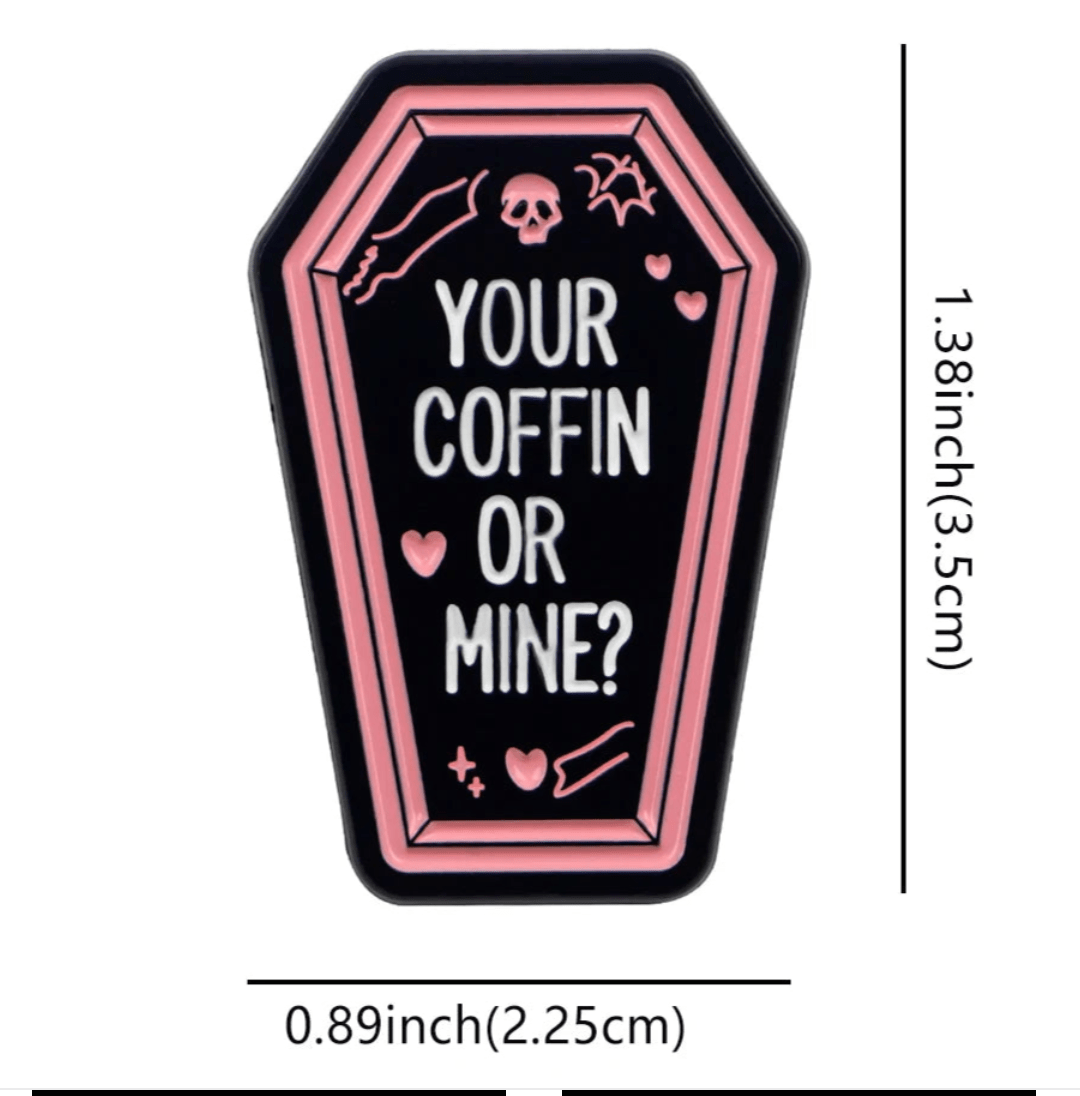 Coffin badge with pink borders, white YOUR COFFIN OR MINE? text, small hearts, skull, and bone. Measures 1.38 x 0.89 (3.5 cm x 2.25 cm).