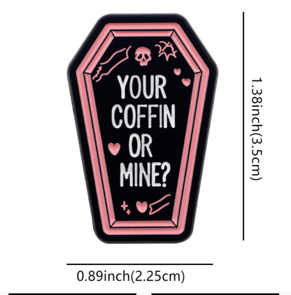 Coffin badge with pink borders, white YOUR COFFIN OR MINE? text, small hearts, skull, and bone. Measures 1.38 x 0.89 (3.5 cm x 2.25 cm).