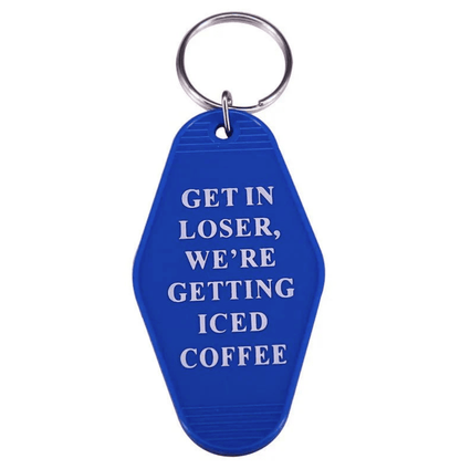 A blue retro hotel key ring from Kiss Me Later with white text: GET IN LOSER, WERE GETTING ICED COFFEE—perfect for pop culture fans.