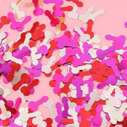 Kiss Me Later adult party confetti shaped like penises, in red, pink, and white, scattered on a pink background.