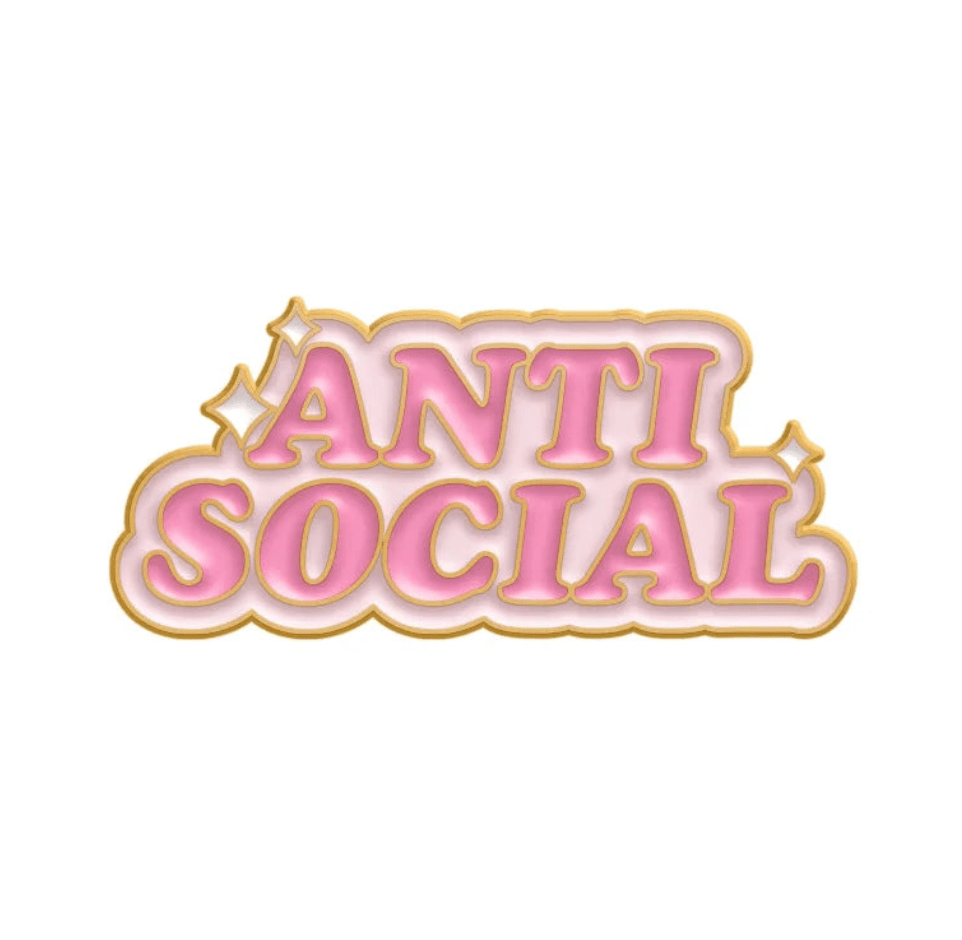 Kiss Me Laters limited edition enamel pin features ANTI SOCIAL in bold pink gradient letters with a gold outline, small gold sparkles, and a white background.
