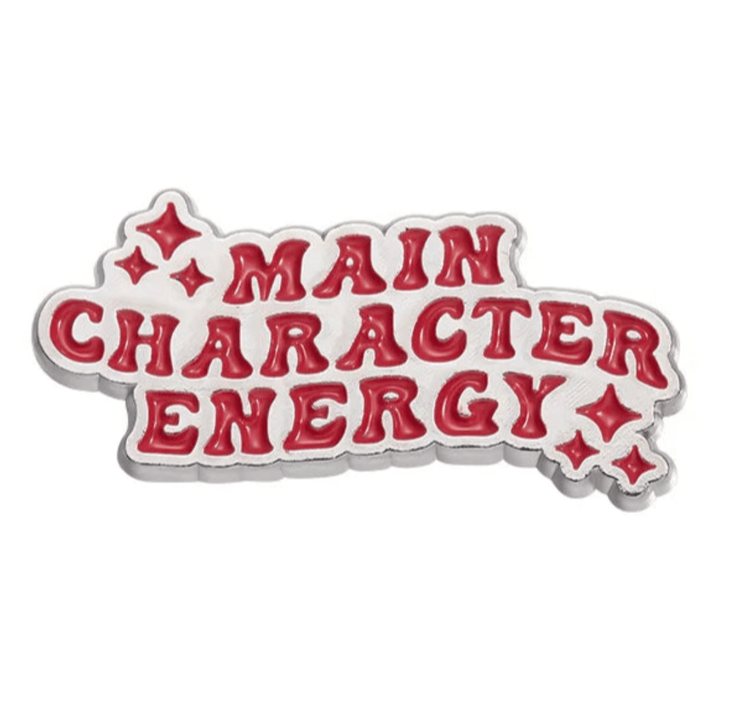 My Cutesy Era’s motivational enamel pin features bold red “MAIN CHARACTER ENERGY” text and small red sparkles, all outlined in silver—the perfect positive affirmation accessory.